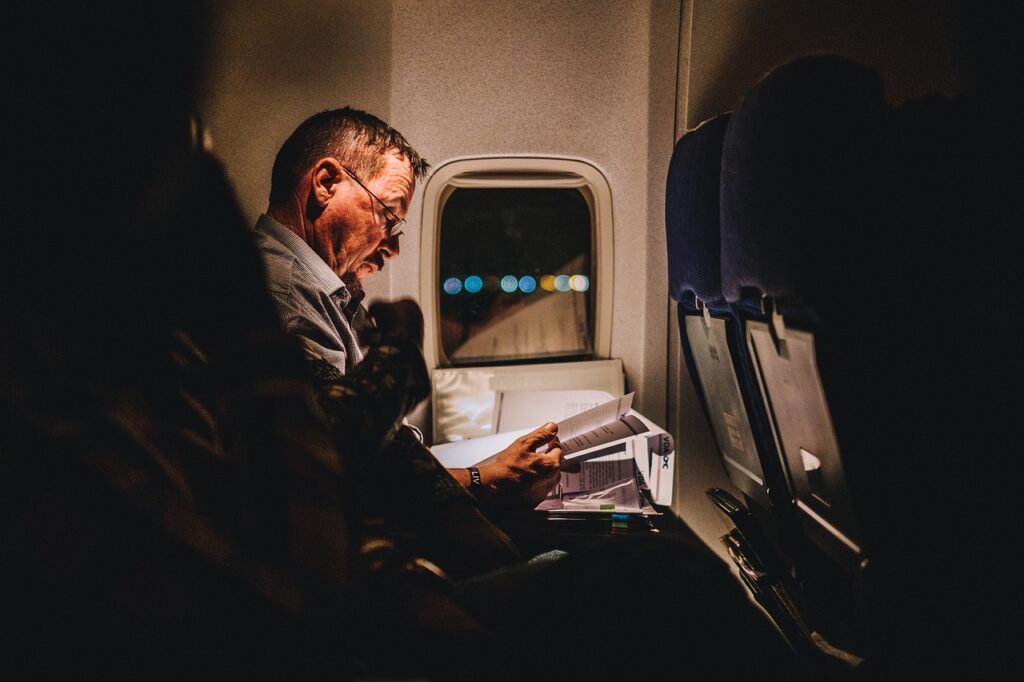 starší muž si čte v noci v letadle